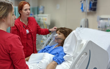Vantage Practical Nursing students assisting "Sally" a health simulator mannequin.