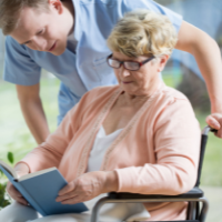 Male caregiver helping elderly woman in wheelchair.